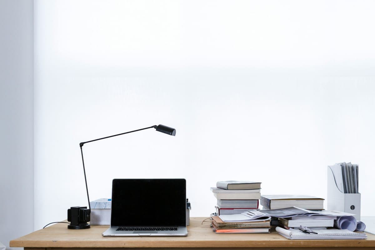 A laptop beside stacks of books.
