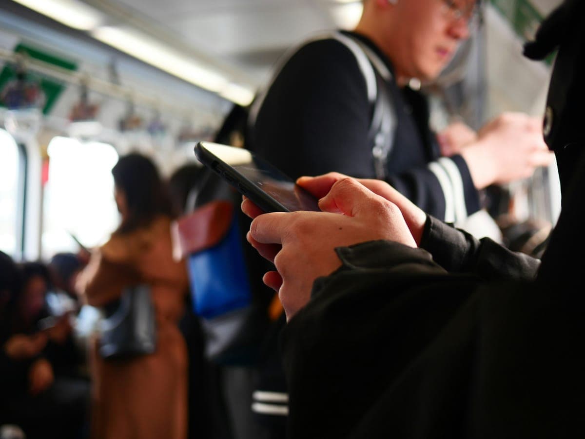 A phone in someone's hand on a subway train.
